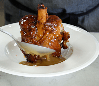 A slow-cooked braised short rib plated with sauce