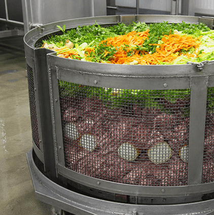 Fresh vegetables layered into a large mesh cooking basket